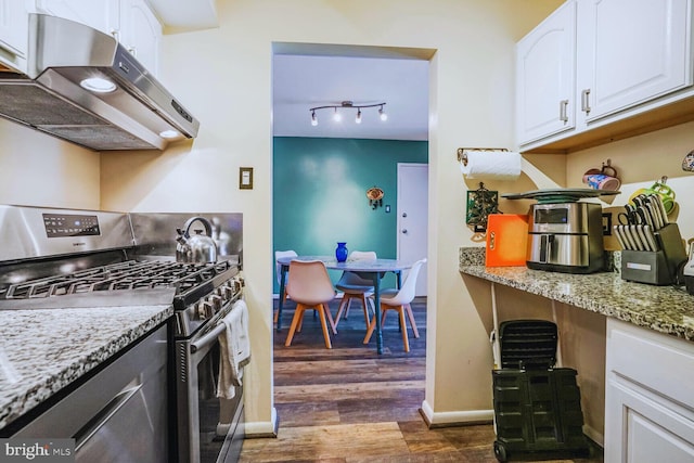 kitchen featuring light stone counters, under cabinet range hood, dark wood-type flooring, white cabinets, and stainless steel gas stove