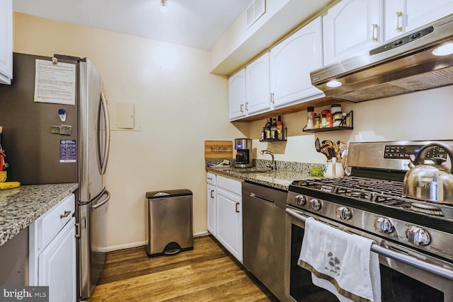 kitchen with stainless steel appliances, white cabinets, under cabinet range hood, and light wood finished floors