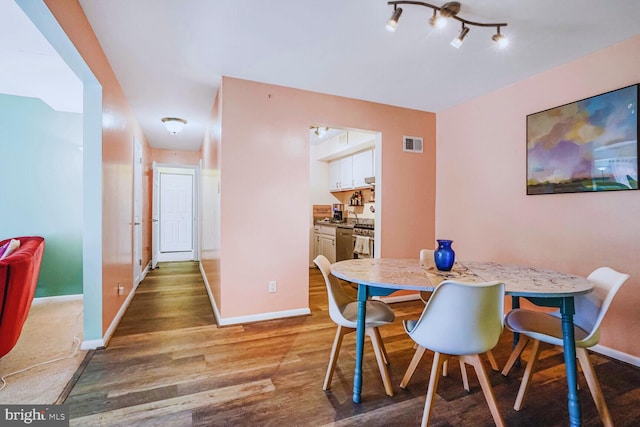 dining space with wood finished floors, visible vents, and baseboards