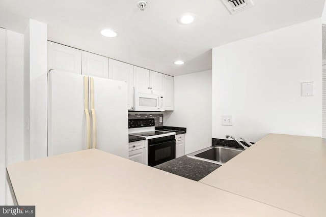 kitchen with a peninsula, white appliances, a sink, visible vents, and white cabinetry