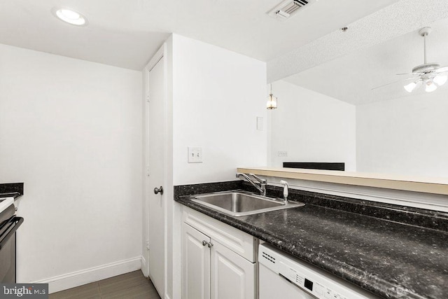 kitchen featuring visible vents, white cabinetry, a sink, ceiling fan, and baseboards