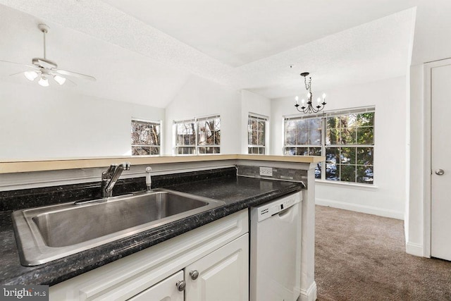 kitchen featuring dark countertops, white dishwasher, a sink, and white cabinets