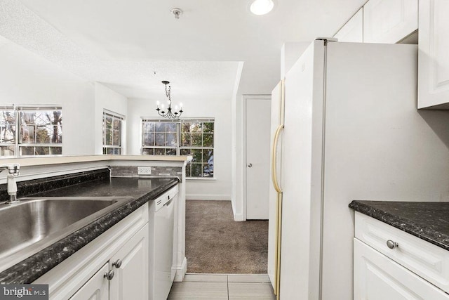 kitchen with light carpet, white appliances, a sink, white cabinetry, and dark stone countertops