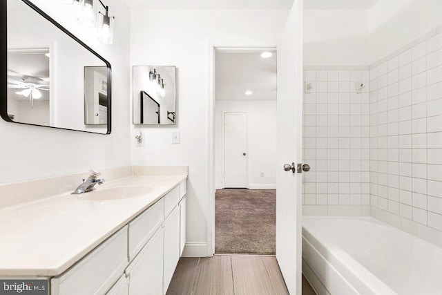 bathroom with shower / bath combination, baseboards, wood finished floors, and vanity