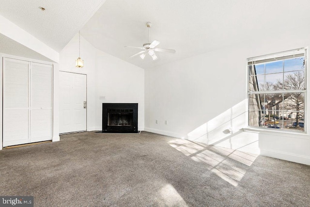 unfurnished living room with vaulted ceiling, a fireplace with flush hearth, carpet flooring, and a ceiling fan