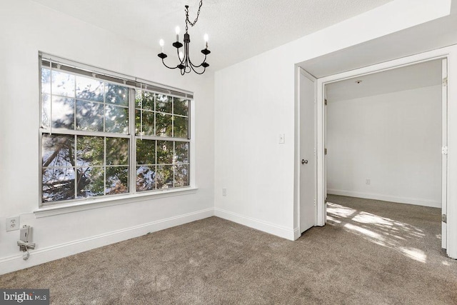 unfurnished dining area with carpet flooring, a notable chandelier, a textured ceiling, and baseboards