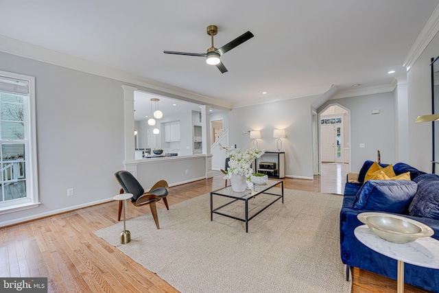 living room featuring ornamental molding, light hardwood / wood-style floors, and ceiling fan