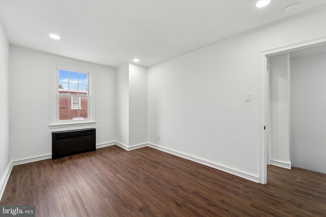 spare room with radiator and dark wood-type flooring