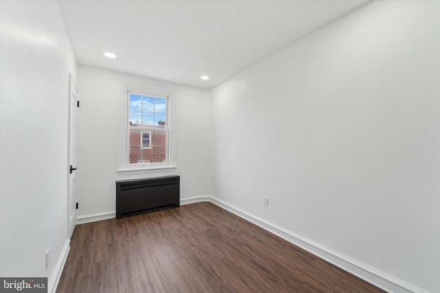 unfurnished bedroom with radiator heating unit and dark hardwood / wood-style floors