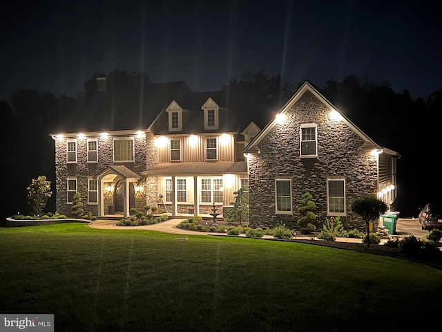 view of front facade featuring stone siding and a lawn