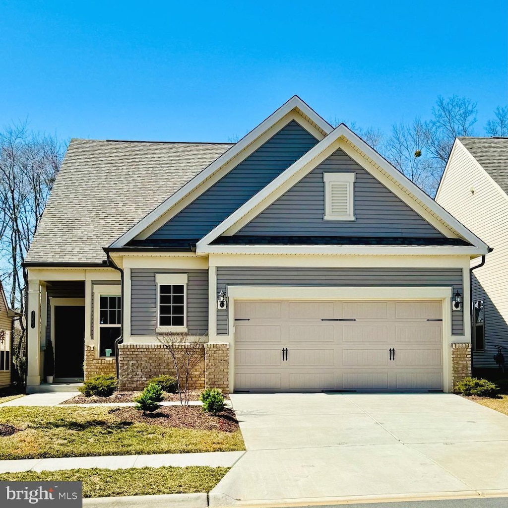 craftsman inspired home with a garage, brick siding, concrete driveway, and a shingled roof