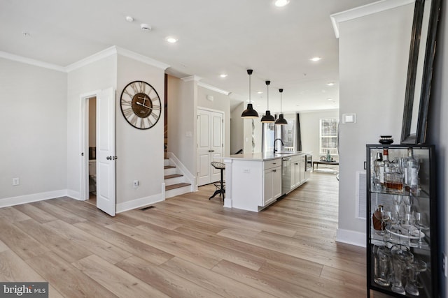 kitchen featuring white cabinets, dishwasher, a breakfast bar, crown molding, and light wood-style floors