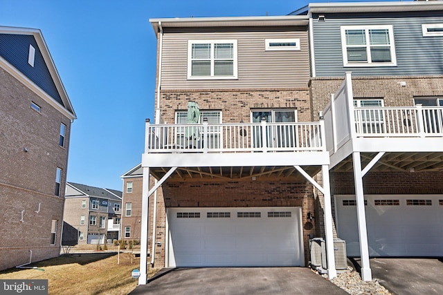 multi unit property featuring driveway, an attached garage, and brick siding