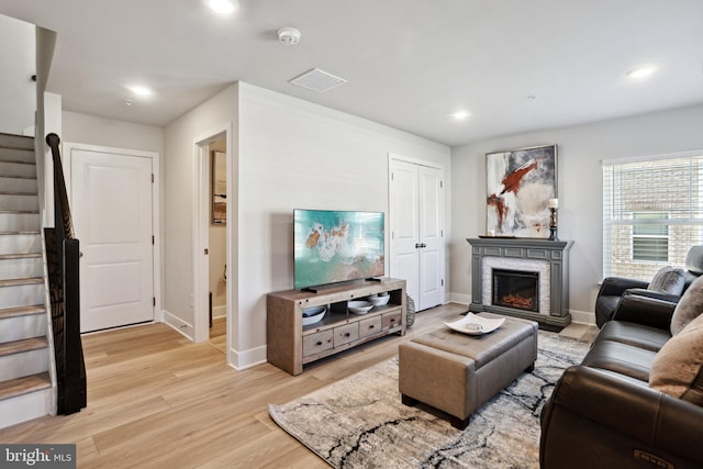 living area with recessed lighting, a fireplace, visible vents, stairs, and light wood-type flooring