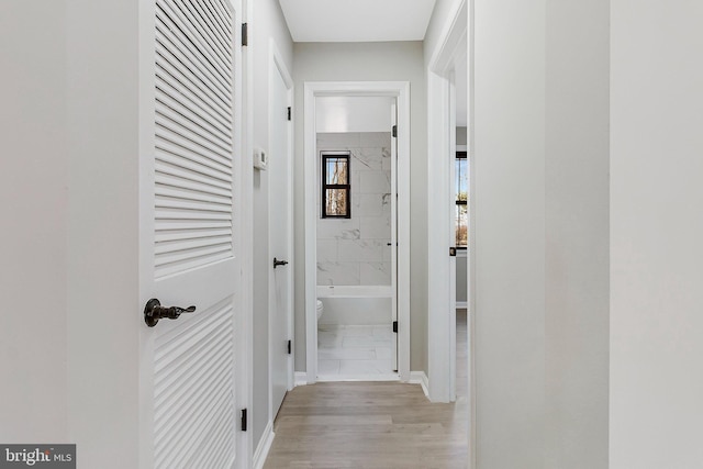 corridor featuring baseboards and light wood finished floors