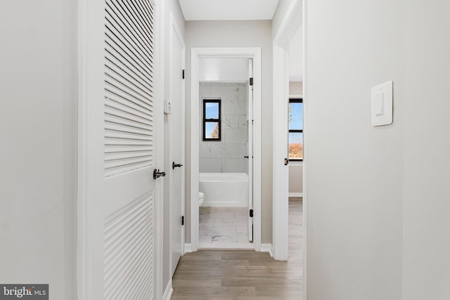 corridor with baseboards and marble finish floor