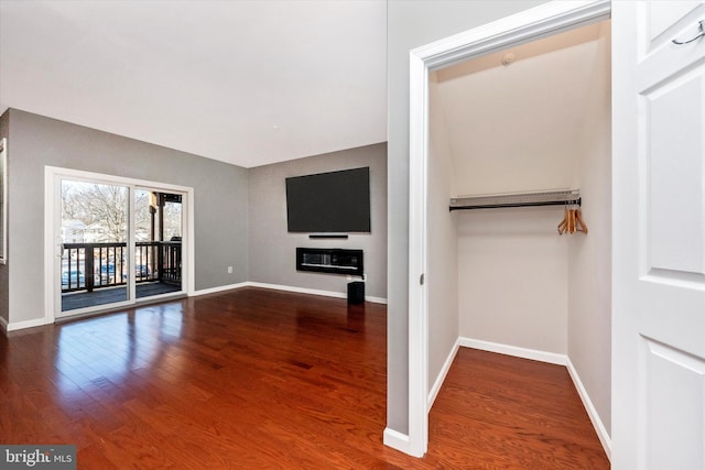 unfurnished living room with a glass covered fireplace, baseboards, and wood finished floors