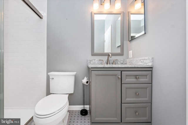 bathroom with toilet, baseboards, tiled shower, and vanity