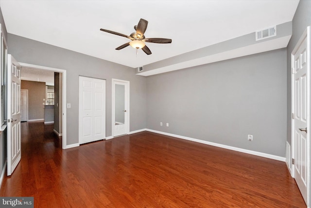 unfurnished bedroom with a ceiling fan, visible vents, baseboards, and wood finished floors