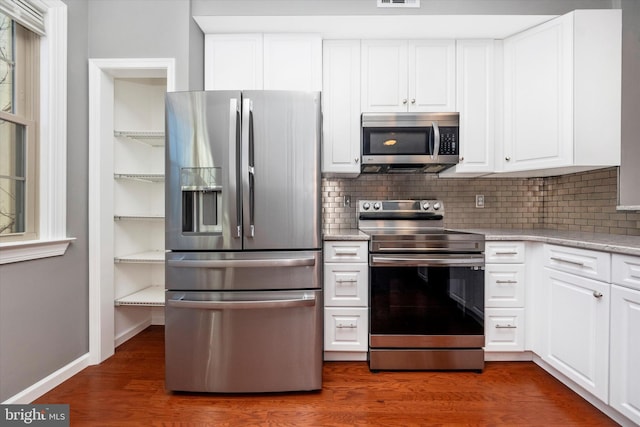 kitchen featuring dark wood-style floors, stainless steel appliances, tasteful backsplash, visible vents, and white cabinetry