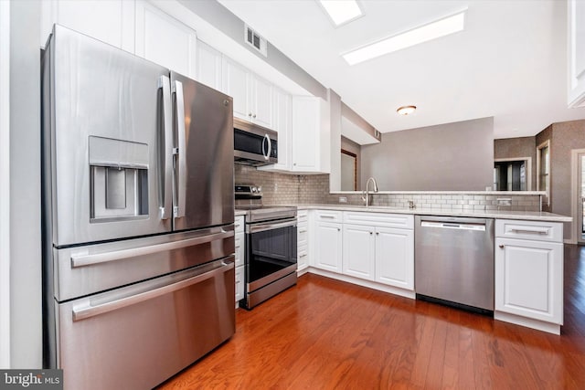 kitchen featuring tasteful backsplash, visible vents, appliances with stainless steel finishes, white cabinets, and a sink