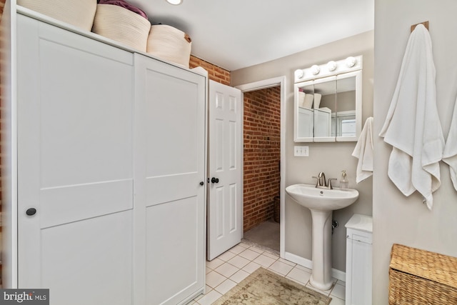 bathroom featuring brick wall, sink, and tile patterned flooring