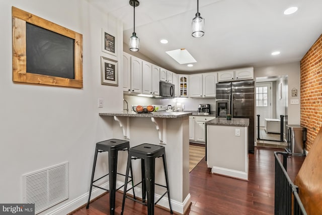 kitchen with a skylight, white cabinetry, pendant lighting, and kitchen peninsula