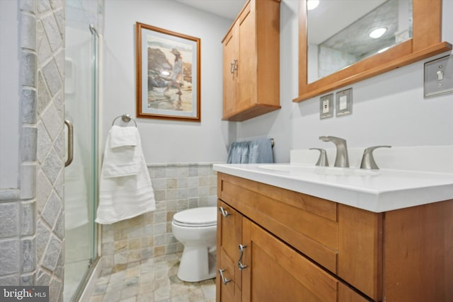 bathroom with vanity, toilet, an enclosed shower, and tile walls