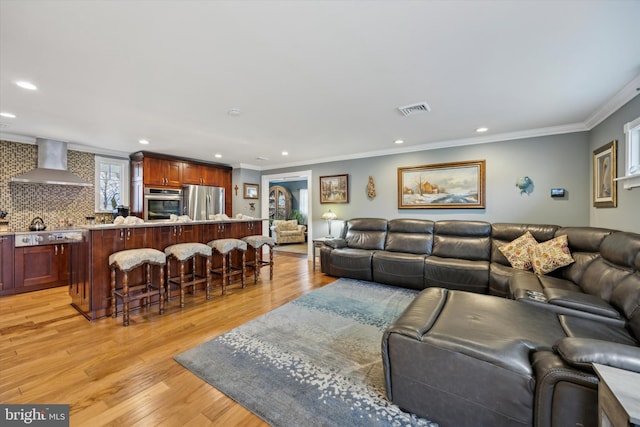 living room featuring crown molding and light hardwood / wood-style flooring