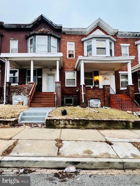 multi unit property featuring covered porch and brick siding