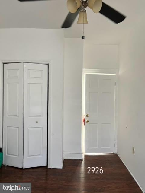 unfurnished bedroom with dark wood-style floors, a closet, and ceiling fan