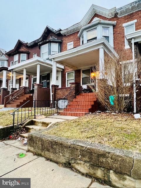 multi unit property with stairway, a porch, and brick siding