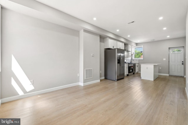 kitchen featuring sink, appliances with stainless steel finishes, white cabinetry, light hardwood / wood-style floors, and a kitchen island