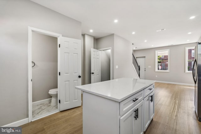 kitchen featuring white cabinetry, light hardwood / wood-style floors, and a center island