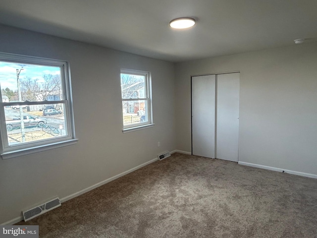 unfurnished bedroom with carpet, a closet, visible vents, and baseboards