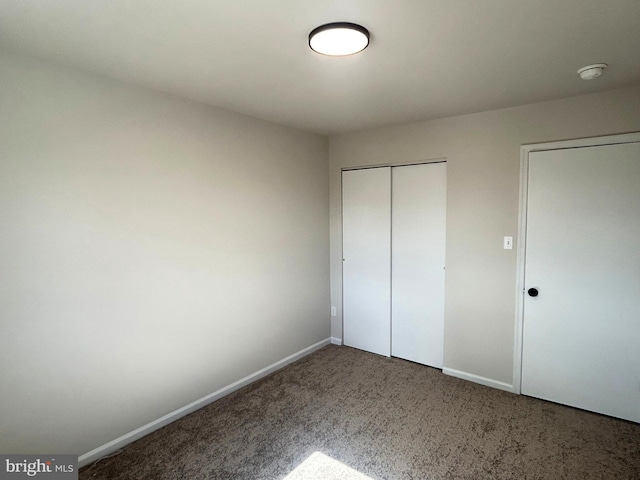 unfurnished bedroom with carpet floors, a closet, and baseboards