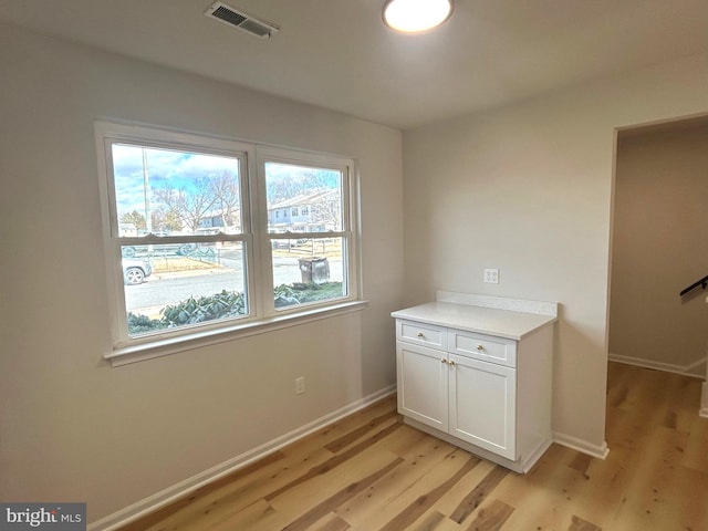 laundry room with light wood-type flooring, baseboards, and visible vents