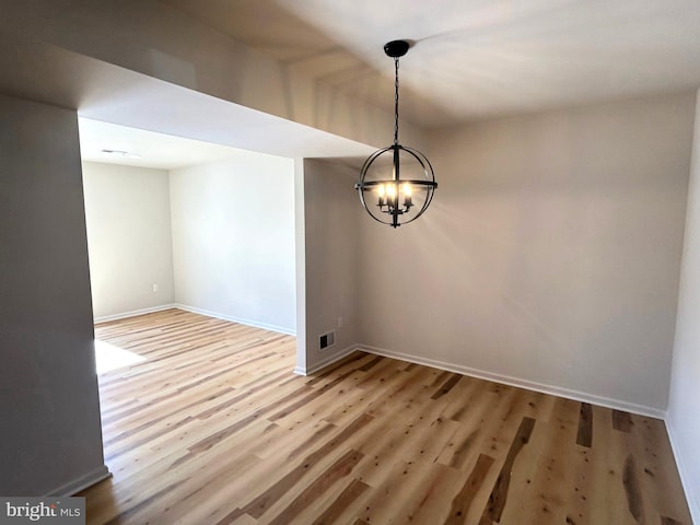 unfurnished room with a notable chandelier, baseboards, visible vents, and light wood-style floors