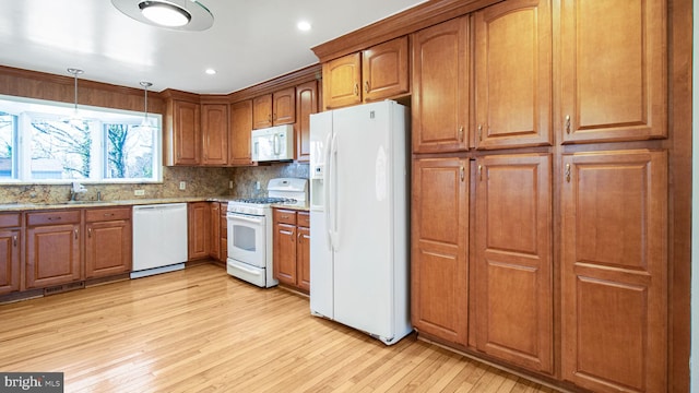 kitchen with pendant lighting, backsplash, light hardwood / wood-style floors, light stone countertops, and white appliances