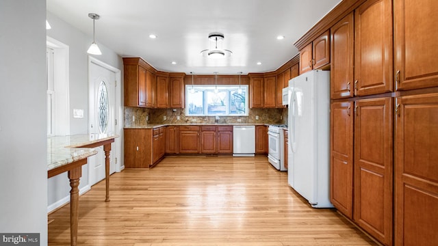 kitchen with white appliances, tasteful backsplash, light stone countertops, decorative light fixtures, and light wood-type flooring