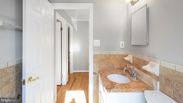 bathroom with hardwood / wood-style floors, vanity, and tile walls