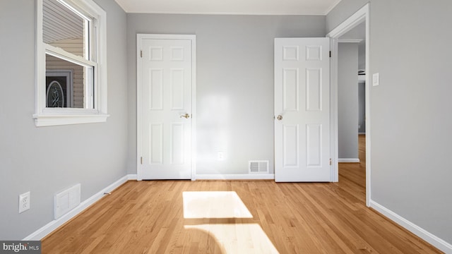 unfurnished bedroom featuring crown molding and light wood-type flooring