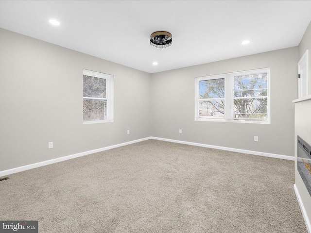 unfurnished room featuring a multi sided fireplace and carpet