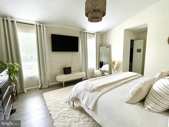 bedroom with wood-type flooring and vaulted ceiling