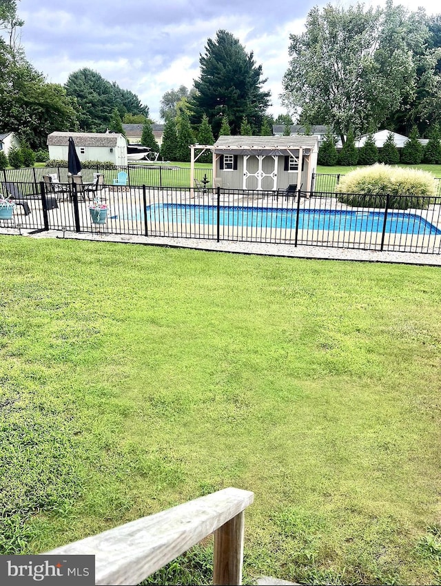 view of swimming pool featuring a yard and an outbuilding