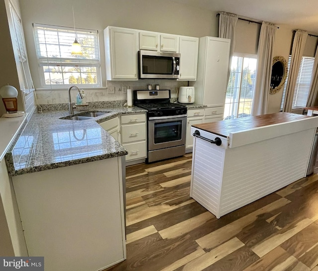 kitchen featuring pendant lighting, sink, appliances with stainless steel finishes, white cabinets, and light wood-type flooring