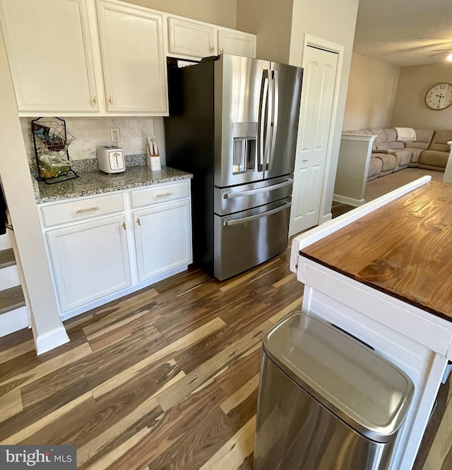 kitchen with dark hardwood / wood-style flooring, white cabinets, light stone counters, and stainless steel fridge with ice dispenser