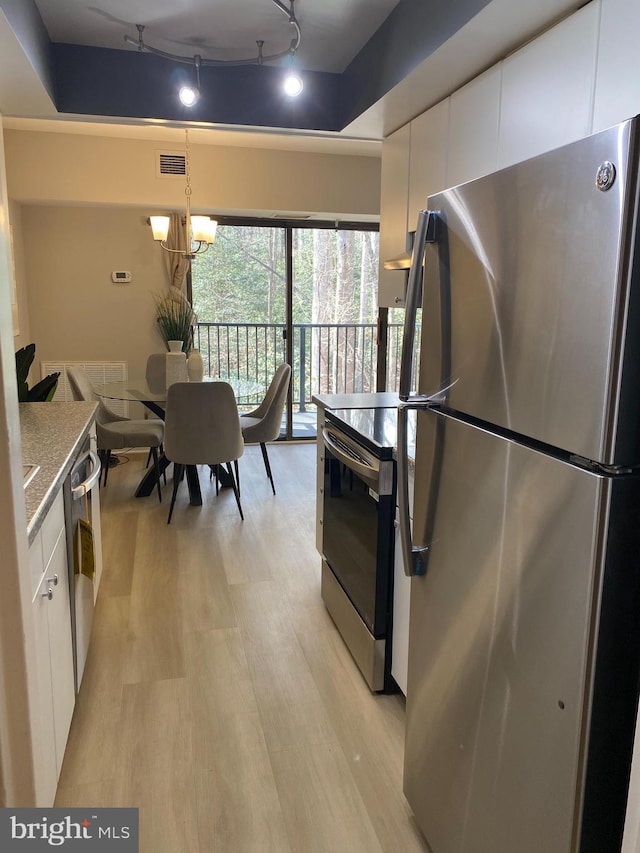 kitchen featuring light countertops, hanging light fixtures, visible vents, appliances with stainless steel finishes, and white cabinets