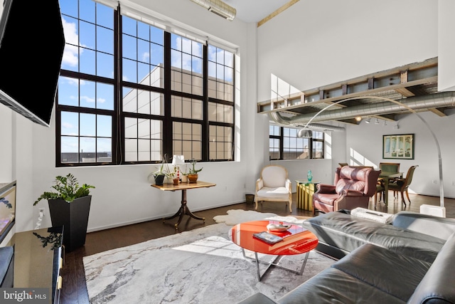 living room with dark wood-type flooring and a high ceiling