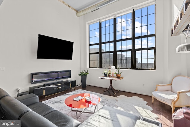 living room with a towering ceiling and dark hardwood / wood-style floors